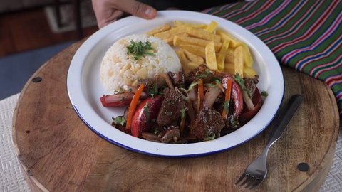 Serving peruvian dish Lomo Saltado in slow motion. Stir fried loin with french fries and rice