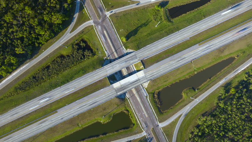 View from above of busy american highway bridge with fast moving traffic in green Florida area. Timelapse of interstate transportation