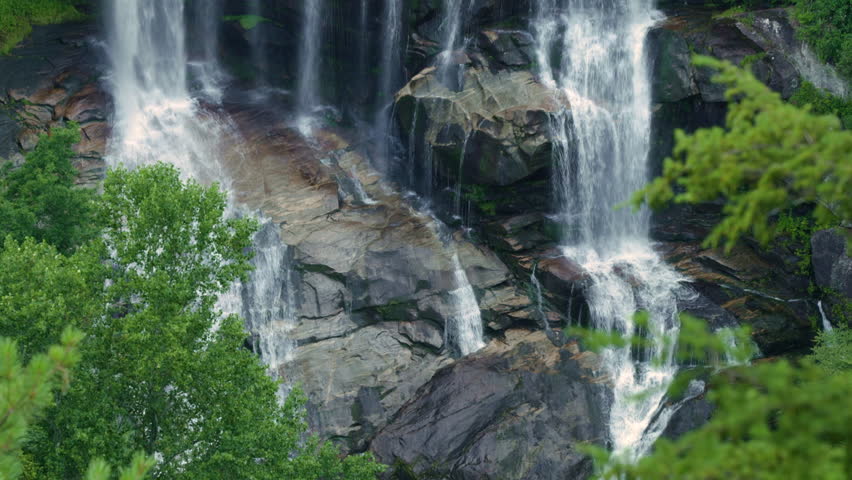Whitewater Falls with falling down clear water from rocky boulders between green lush woods in Nantahala National Forest, North Carolina, USA