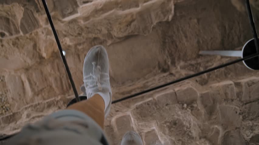 First point view. Museum of archaeological excavations under glass. Historical artifacts. Top view of a tourist's feet walking on a sturdy glass surface. Royalty-Free Stock Footage #3440778937