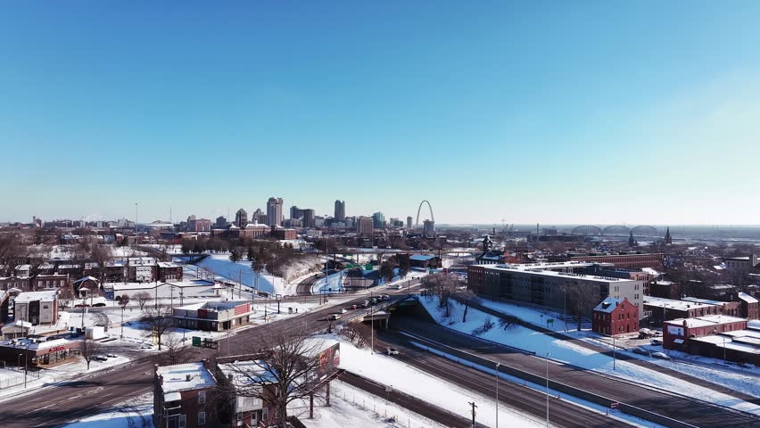 Aerial footage of Saint Louis, Missouri on a cold and snowy winter morning with clear blue skies and snow on the ground.
