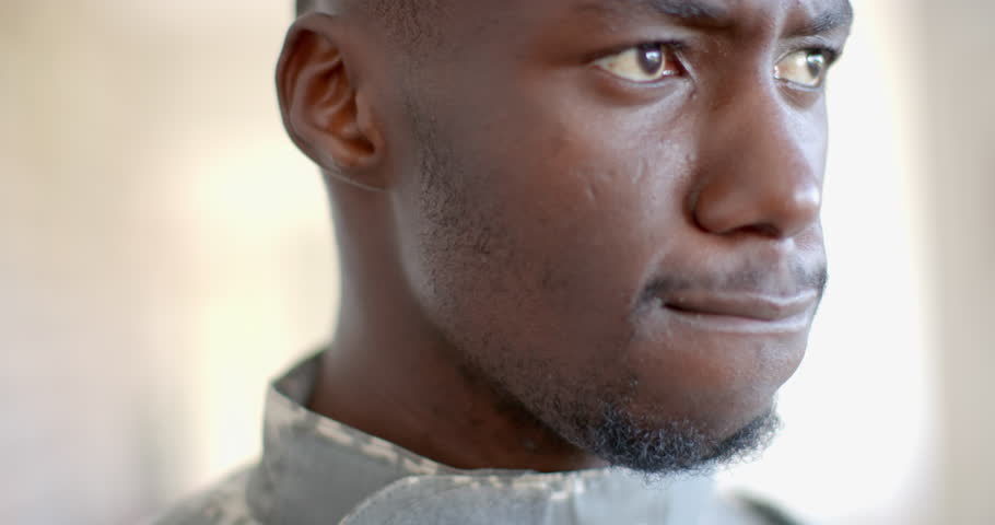 Young African American soldier looks thoughtfully to the side, with copy space. Captured indoors, the image exudes a sense of contemplation or decision-making, slow motion. Royalty-Free Stock Footage #3440854157