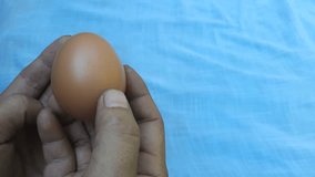 A man's hand holds a European chicken egg on a white background. Protein food from poultry eggs