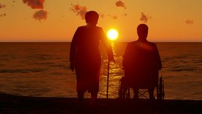 Silhouette video of elderly couple watching the sea at sunset