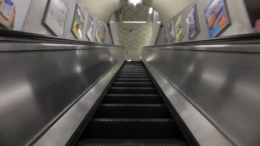 Low angle traveling view of escalator going downward in a building in London