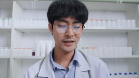 Asian male pharmacist or doctor talking with patients via video call explaining drug information and online counseling at hospital. Healthcare and technology online.