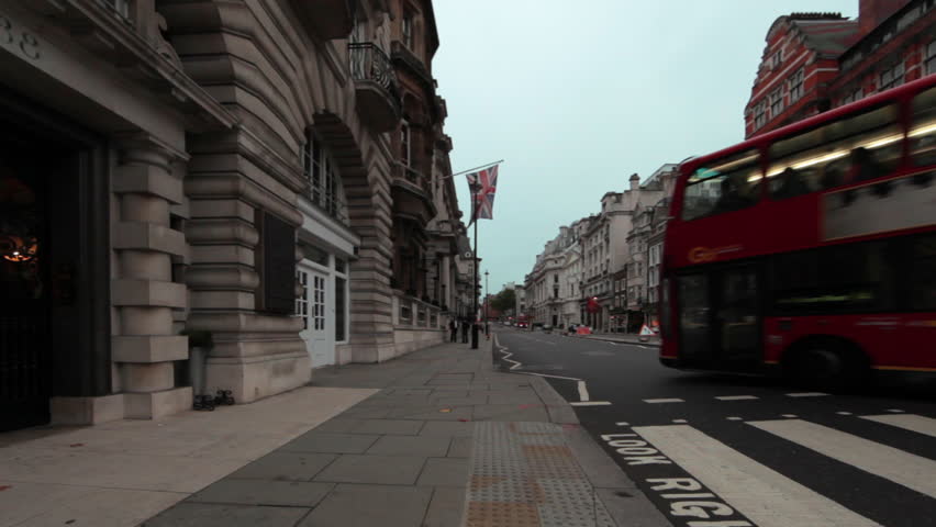 Cars driving down the street with several red double decker buses and buildings