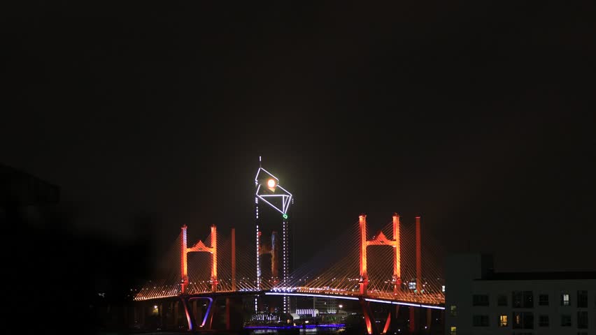 Blurred video background of colorful night lights. Beautiful bokeh is created along the bridge over the river and there is heavy traffic.