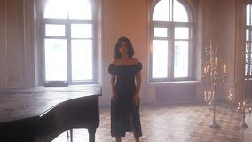 a woman in a black dress is standing in front of a piano in a room