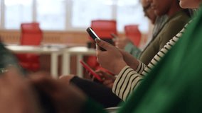 Closeup tracking shot of unrecognizable multicultural business people sitting in row using smartphones, waiting for job interview, sitting in queue line row in chairs in modern office waiting room. - Powered by Shutterstock - Get 15% off with code: PIKWIZARD15