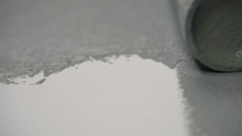Man painting wall with grey paint using roller.. Roller painting white wall with grey paint. Close up