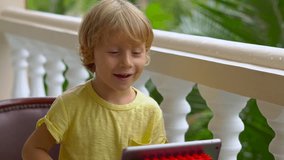 boy in tropics talking with friends and family on video call using a tablet and wireless headphones