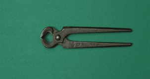Vintage cutting pliers in action on green color background. Loopable stop motion animation. 4K top view. DIY video concept.