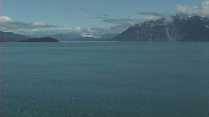 Wide shot of Glacier Bay in Alaska with small mountain peaks in the background.