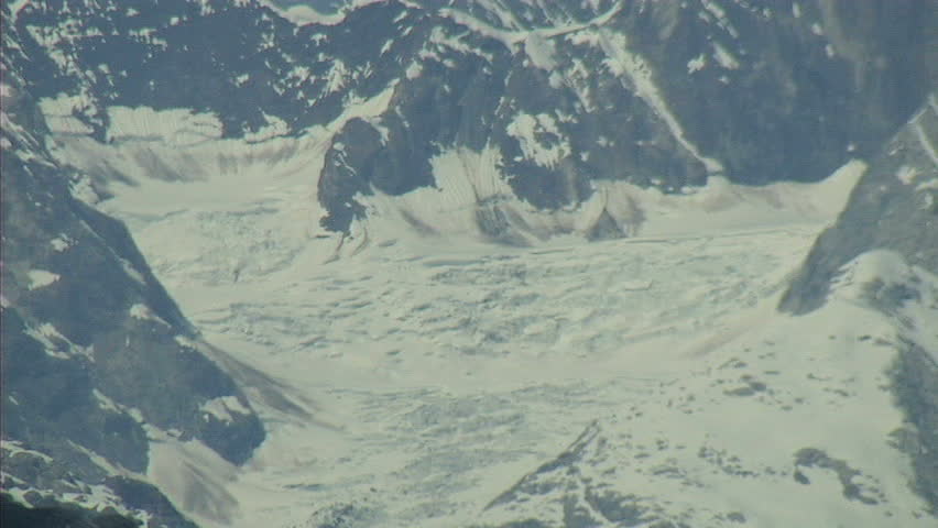 CU shot of one of the many snow capped giant mountain peaks that surround Glacier Bay, Alaska.  The shot pulls out to reveal the rest of the landscape.