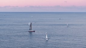 Aerial view on sailboats after scenic sunset at Waikiki shore. Sunset cruise on Oahu island. Hawaii active water sport or tourism background. Tourist attraction on sailing ships. People enjoy seascape