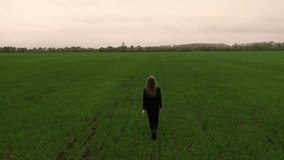 A girl in black clothes, a European woman with long hair, walks run across a green field in a blue disposable protective mask from viruses, in a respirator. pandemic covid-19. Coronavirus. Drone view - Powered by Shutterstock - Get 15% off with code: PIKWIZARD15