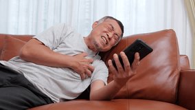 An elderly Asian man with severe heart pain holds a smartphone and calls an emergency sickness hotline for help. Elderly heart disease. heart failure - Powered by Shutterstock - Get 15% off with code: PIKWIZARD15