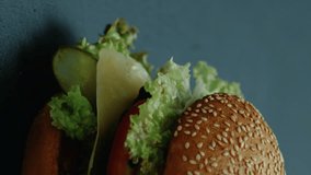 Vertical video. Unhealthy burger. Fast food. Delicious hamburger american cuisine junk nutrition cheeseburger isolated on dark background.
