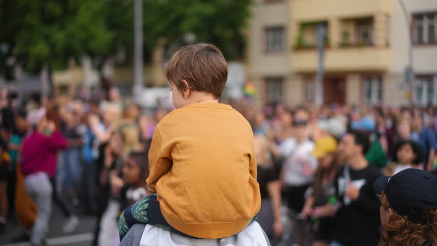 Little kid sit father shoulders. Many gay people crowd protest against homophobia. Family walk lgbt pride parade. Child watch strike demonstration. Parents show csd fest day to boy son. Peaceful rally