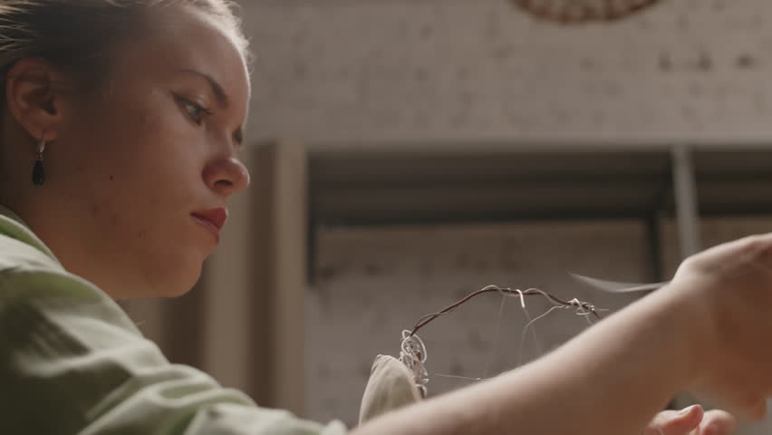 Waist up of concentrated young Caucasian female sculptor using armature wire while shaping form of human skull to make clay head in small workshop Royalty-Free Stock Footage #3441622579