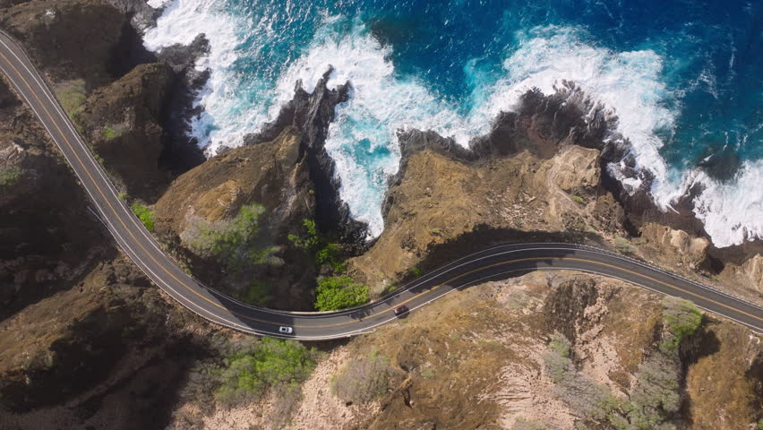 Overhead view of rocky mountain landscape car driving by Hawaii island. Coastline road with scenic ocean view. Road trip. Aerial view cars driving by cinematic rocky coast. Driving by Oahu island road