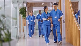 Multi cultural medical team wearing scrubs with digital tablet walking along corridor in modern hospital corridor - shot in slow motion - Powered by Shutterstock - Get 15% off with code: PIKWIZARD15