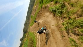 Vertical video. FPV of riders on a motocross track in slow motion.