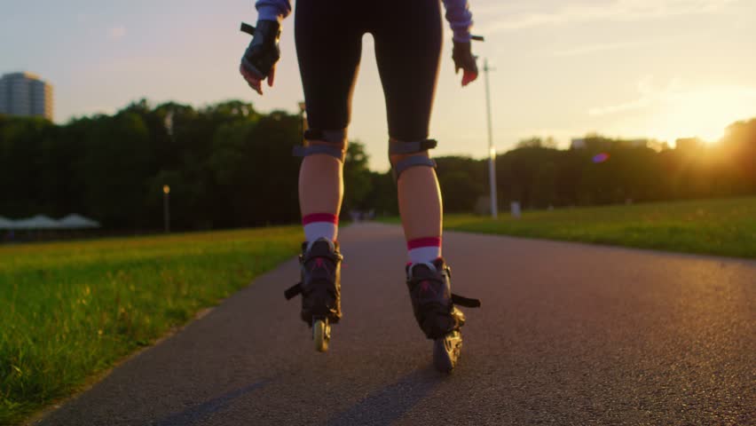 Back view of unrecognizable young woman rollerblading in the park