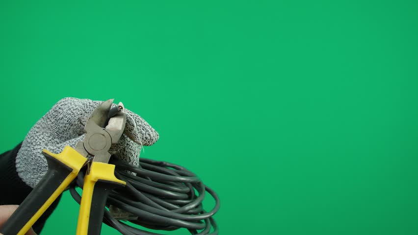 Black and yellow wire cutters, side wire cutters, a man's hand in gray gloves holds them on a green background Royalty-Free Stock Footage #3441784557