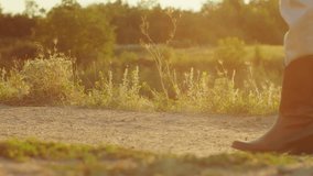 Cowboy boots and beige pants on a dusty trail. Country lifestyle and western fashion concept. Design for outdoor apparel, adventure blog, rural life promotion. Ground level view with sunset light and - Powered by Shutterstock - Get 15% off with code: PIKWIZARD15