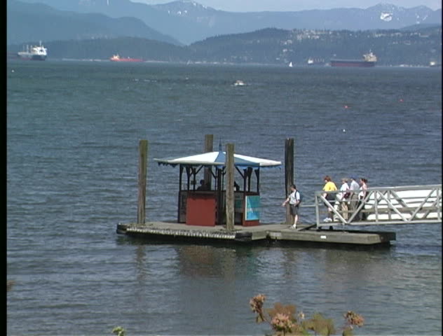 Passengers on float wait for aqua ferry on Vancouver, BC waterfront.