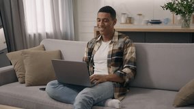 Smiling African American man relaxing at couch apartment biracial ethnic male guy on sofa home mortgage loan user freelancer student businessman using pc laptop computer online shopping pay browsing - Powered by Shutterstock - Get 15% off with code: PIKWIZARD15