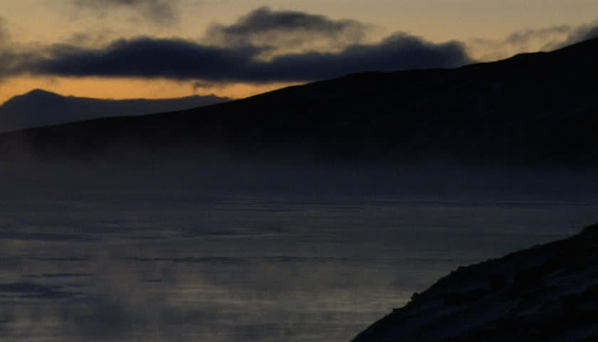 Mist and fog over water with sunset in background