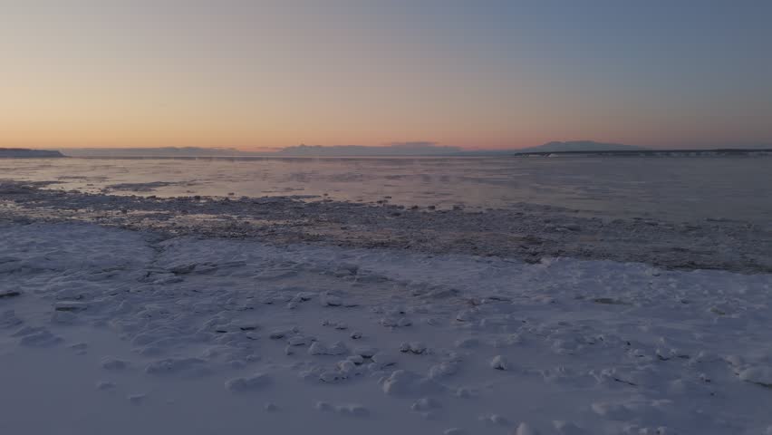 Drone dolley view of horizon colored with sunset colors over a frozen lake in Alaska