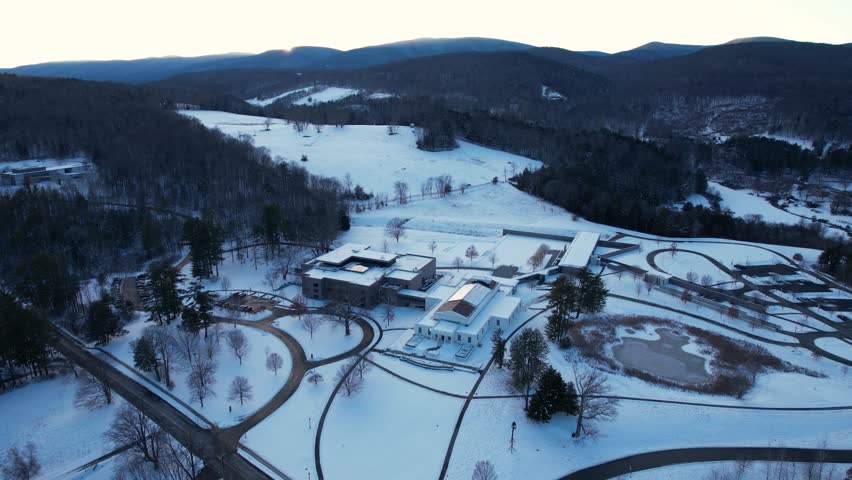 Sunset over snow blanketed hill sheltering a museum and arts complex among forests of hardwoods and evergreens. Located in Williamstown, Massachusetts, New England, United States