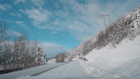 POV video of driving through Norway's Western Fjords in winter, showcasing a journey along snowy roads. The route offers scenic views of towering mountains and majestic fjords amidst heavy snowfall.