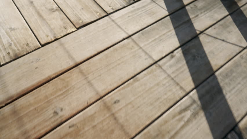 A man walks on the wooden floor of a terrace near his house covered with melted snow.
