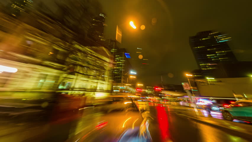 Back car window view of long exposure time laps of the highway in the city. City at night timelapse. Driving a car, the city at night. Camera at the vehicle back trunk glass. Rainy night soft glowing.