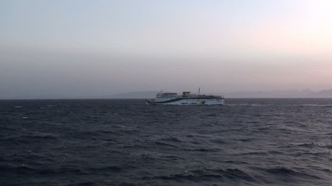 Aegean Sea, Saronic Gulf / Greece - December 1, 2012: Long distance shot of a big ship that travels during the nightfall.