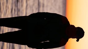 Silhouette of an unrecognizable man against the backdrop of the sea at sunset. Vertical video. Rovinj, Croatia - February 13, 2024 - Powered by Shutterstock - Get 15% off with code: PIKWIZARD15