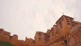 View of royal buildings at Jaisalmer fort in Jaisalmer, Rajasthan, India. Fort in the desert of Jaisalmer. Beautiful slow motion video of some pigeons flying on the Jaisalmer fort. 