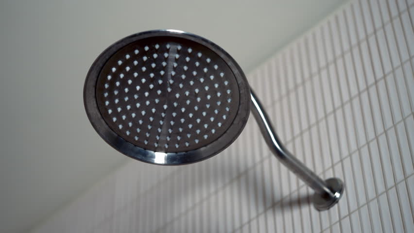 Close-up of a wall-mounted and flush-mount shower head in a round shape with water flowing out of it. Royalty-Free Stock Footage #3442180935