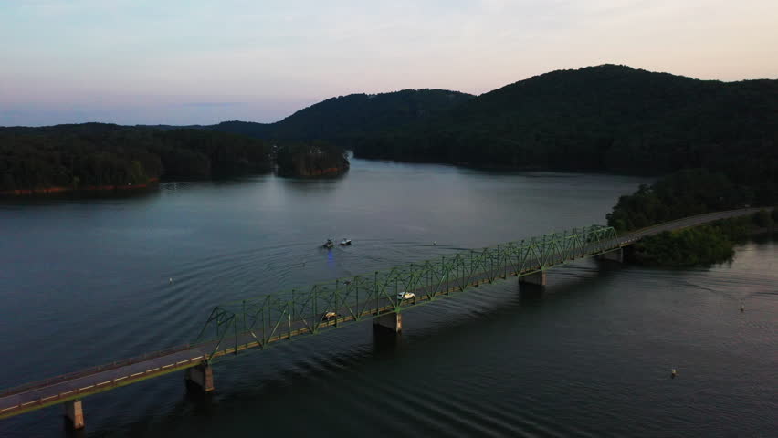 Aerial footage of vehicles passing on trust road bridge over Lake Allatoona. Police boat nearing to motorboat. Evening view of nature scene. Atlanta, Georgia, USA