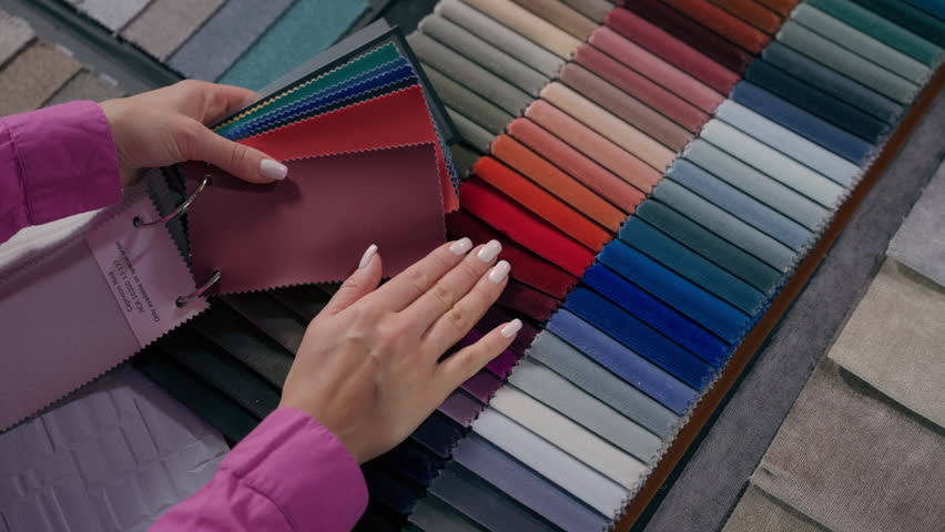 Close up details fabric swatches different trend colors sample collection on table unrecognizable woman customer comparing color shades touching upholstery material for furniture and interior design
