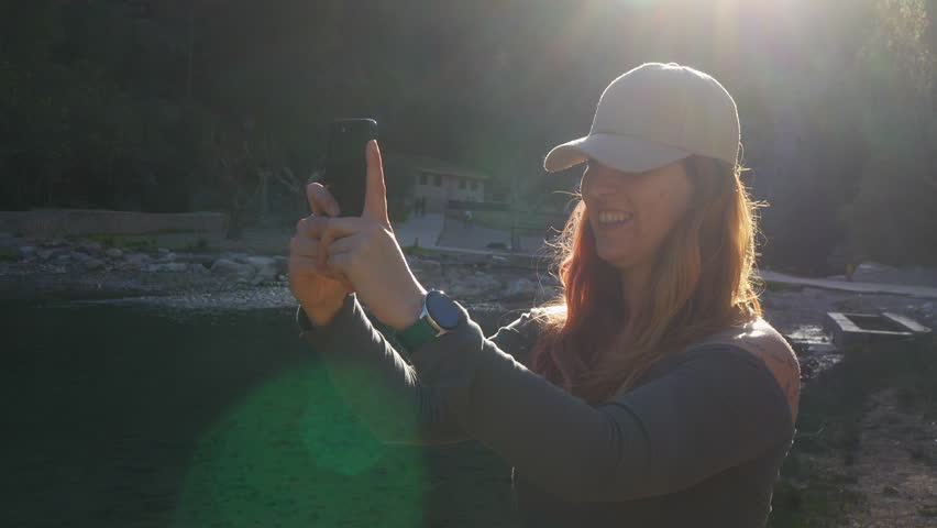 Back view of a woman using a smartphone by the river.