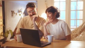 Young happy couple drinking tea, watching movie on laptop, hugging and laughing when enjoying leisure time together at home - Powered by Shutterstock - Get 15% off with code: PIKWIZARD15