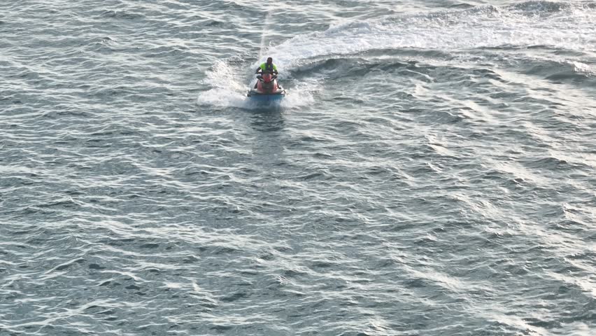 Person on Jet ski riding at high speed towards camera, Aerial tracking