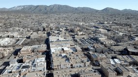 Downtown Santa Fe, New Mexico and mountains with drone video wide shot moving in a circle.
