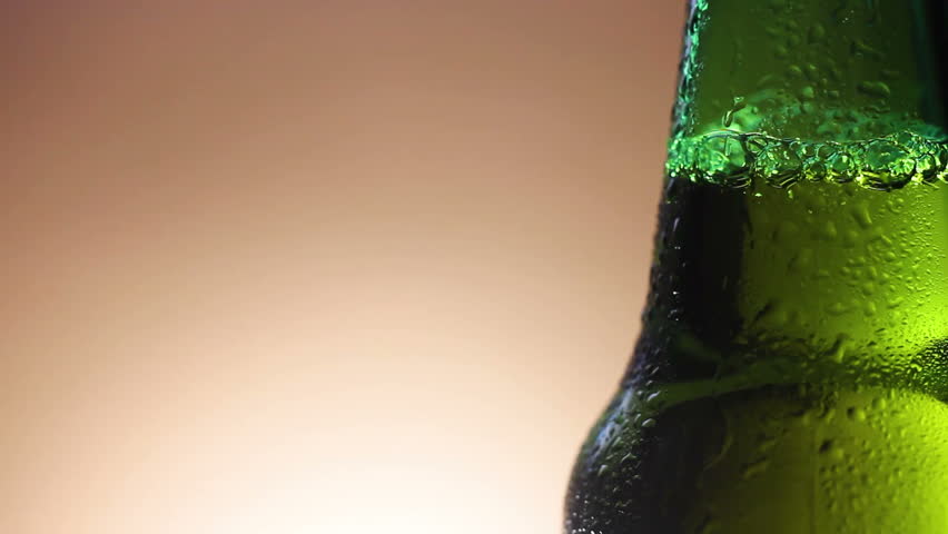Drop of condensate drains on a green bottle of beer.